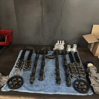 Arbres à cames et pignons de distribution alignés sur un tapis d'atelier.